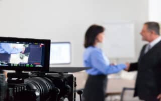 Corporate video shoot of business professionals shaking hands in a Denver office setting.