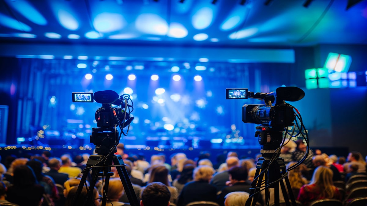 Livestream vs. Post-Produced Event Video Which Delivers More ROI Livestream video production setup with cameras recording a live event stage performance.